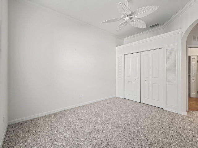 unfurnished bedroom featuring ceiling fan, ornamental molding, carpet floors, and a closet