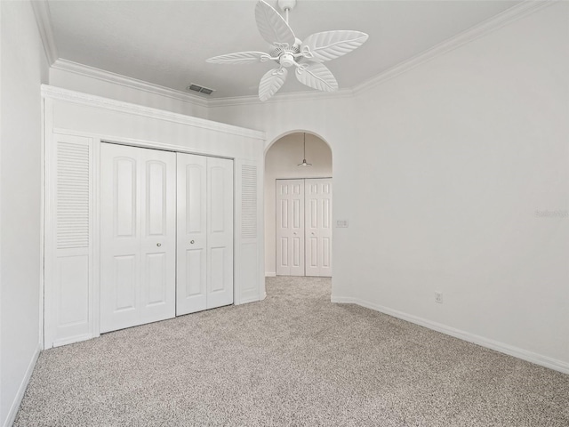 unfurnished bedroom with ceiling fan, a closet, light colored carpet, and ornamental molding