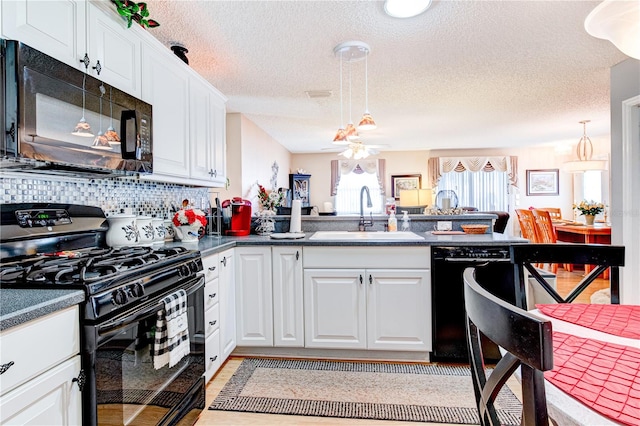 kitchen with a textured ceiling, black appliances, white cabinets, backsplash, and sink