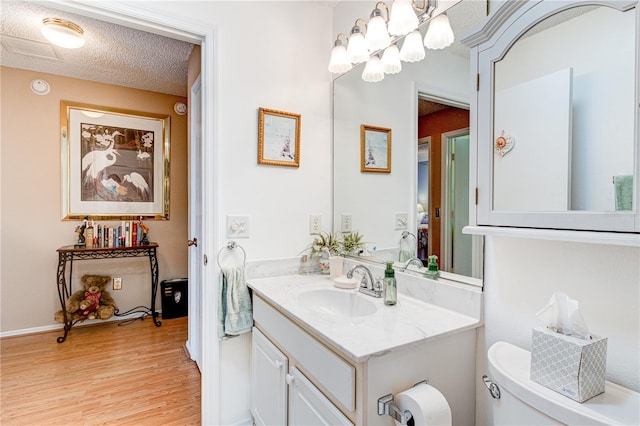 bathroom featuring large vanity, toilet, hardwood / wood-style flooring, and a textured ceiling