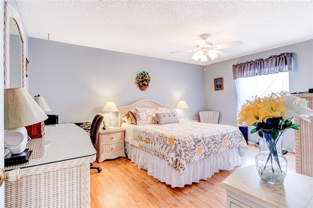 bedroom featuring ceiling fan, light wood-type flooring, and a textured ceiling