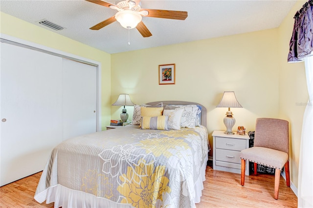 bedroom featuring light hardwood / wood-style floors, a textured ceiling, a closet, and ceiling fan