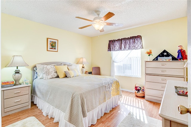 bedroom featuring light hardwood / wood-style flooring, ceiling fan, and a textured ceiling