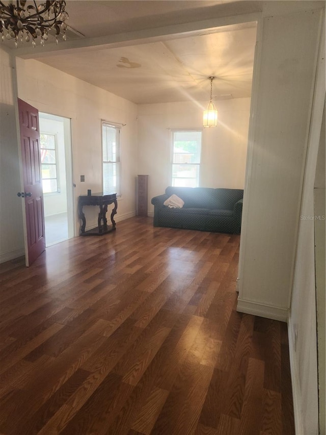 living room featuring a healthy amount of sunlight, dark hardwood / wood-style floors, and a notable chandelier