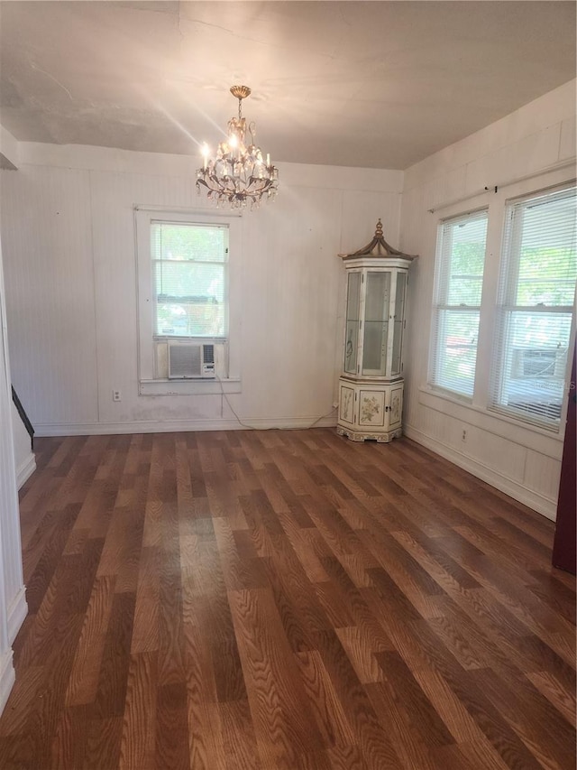 unfurnished living room with dark hardwood / wood-style flooring, plenty of natural light, and a notable chandelier