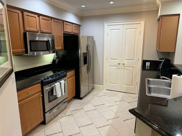 kitchen with stainless steel appliances, light tile floors, dark stone counters, ornamental molding, and sink