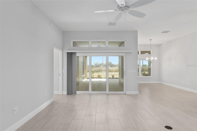 spare room with ceiling fan with notable chandelier