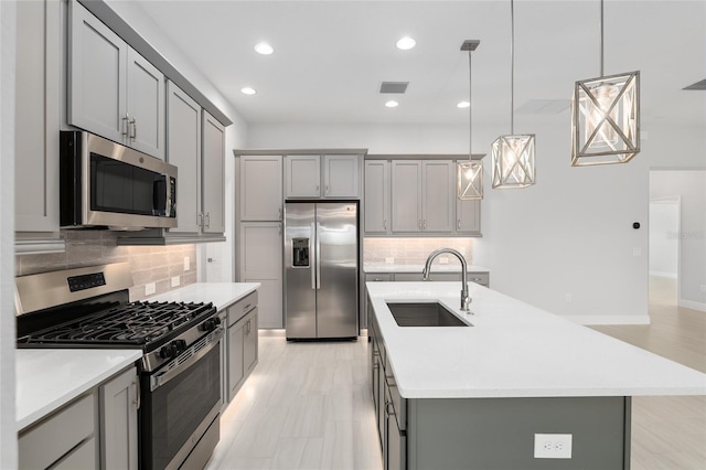 kitchen with a center island with sink, tasteful backsplash, appliances with stainless steel finishes, and sink