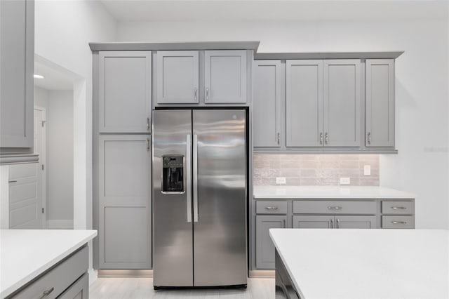 kitchen featuring gray cabinetry, stainless steel refrigerator with ice dispenser, and decorative backsplash