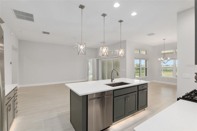 kitchen featuring hanging light fixtures, a kitchen island with sink, dishwasher, sink, and light hardwood / wood-style flooring