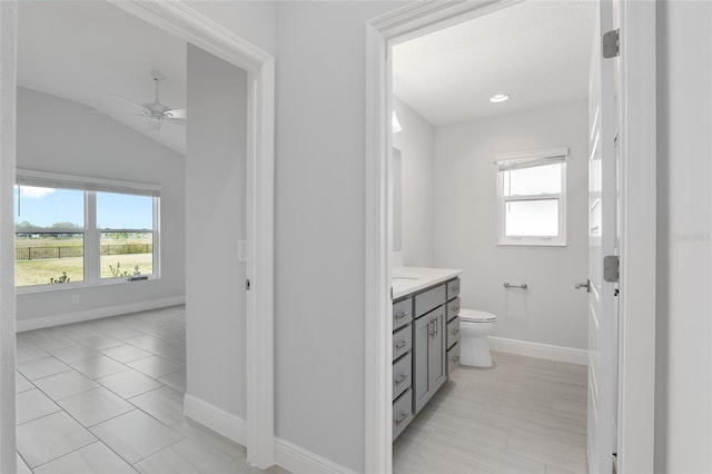 bathroom with toilet, vaulted ceiling, ceiling fan, tile patterned floors, and vanity