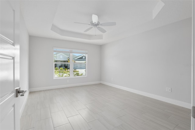 spare room featuring ceiling fan and a raised ceiling