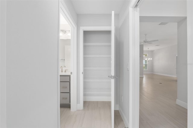 hallway featuring sink and an inviting chandelier