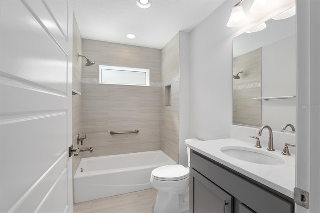 full bathroom featuring vanity, tiled shower / bath combo, and toilet