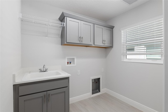 clothes washing area featuring hookup for a washing machine, sink, and cabinets