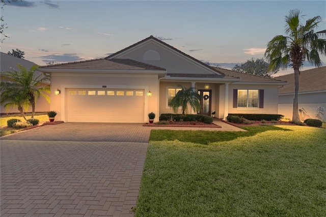 view of front of home with a garage and a lawn