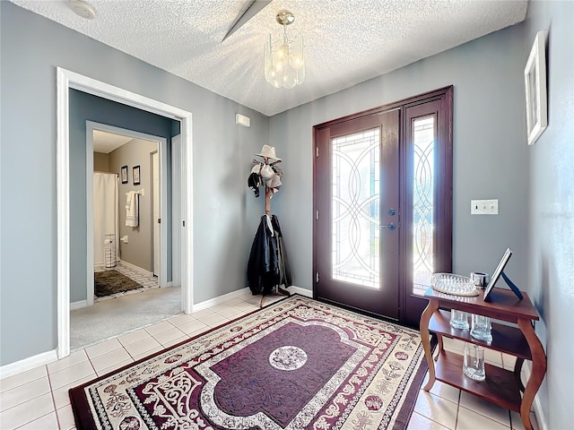 foyer featuring an inviting chandelier, a textured ceiling, and light tile floors