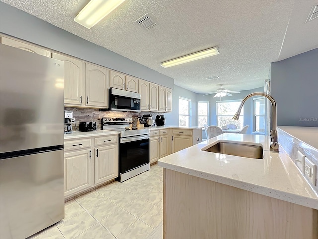 kitchen with backsplash, ceiling fan, sink, stainless steel appliances, and light tile floors