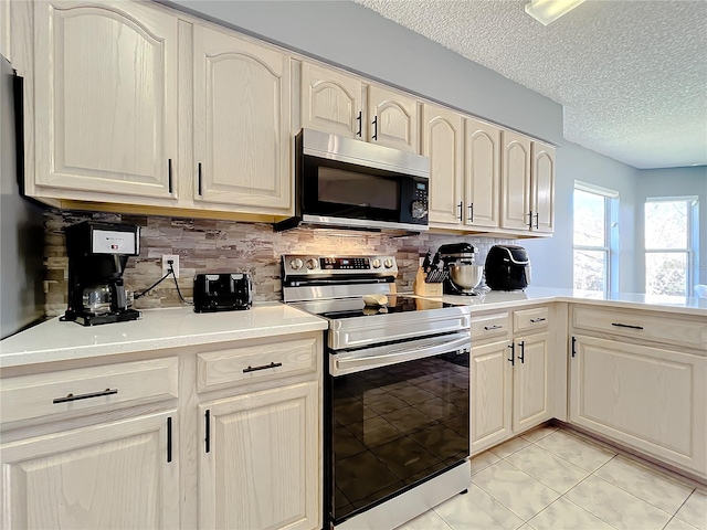 kitchen with light tile floors, appliances with stainless steel finishes, a textured ceiling, and tasteful backsplash