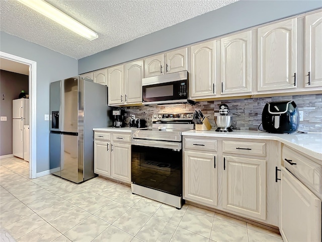 kitchen featuring tasteful backsplash, a textured ceiling, appliances with stainless steel finishes, and light tile floors