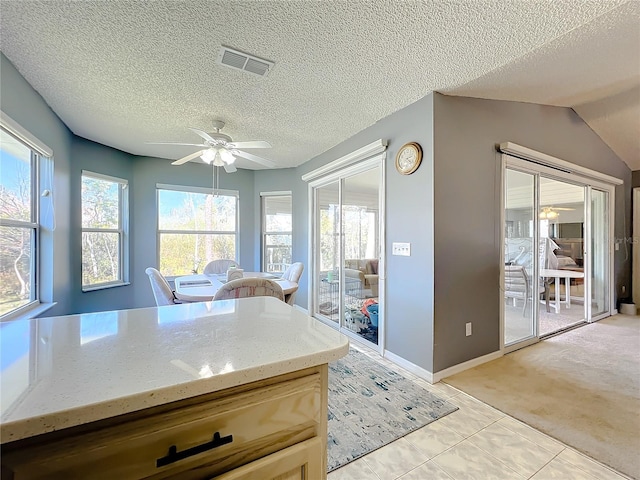 kitchen with light carpet, a textured ceiling, ceiling fan, and light stone countertops