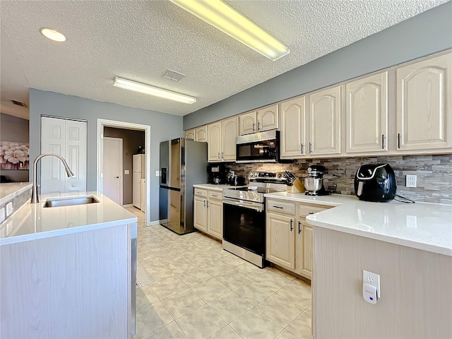 kitchen featuring backsplash, appliances with stainless steel finishes, sink, light tile floors, and a textured ceiling