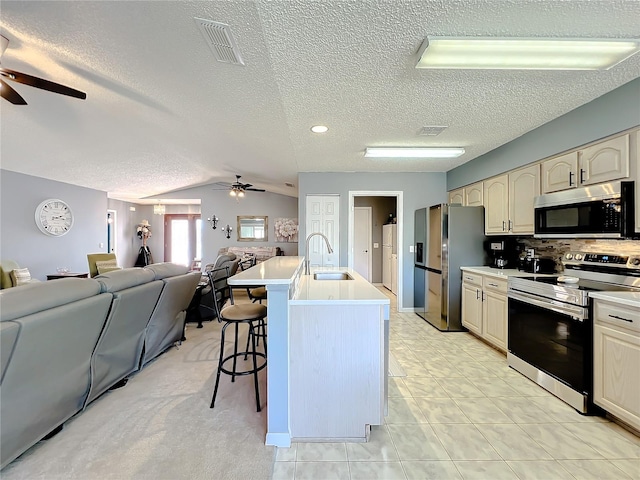 kitchen with ceiling fan, appliances with stainless steel finishes, a breakfast bar, and sink