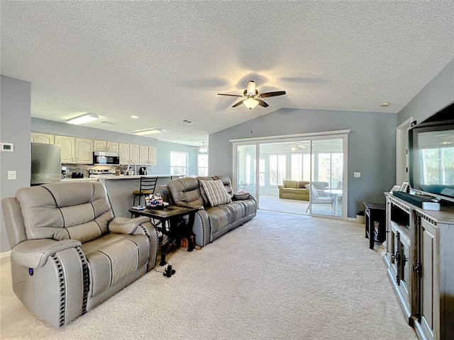 carpeted living room featuring lofted ceiling, a textured ceiling, ceiling fan, and a wealth of natural light