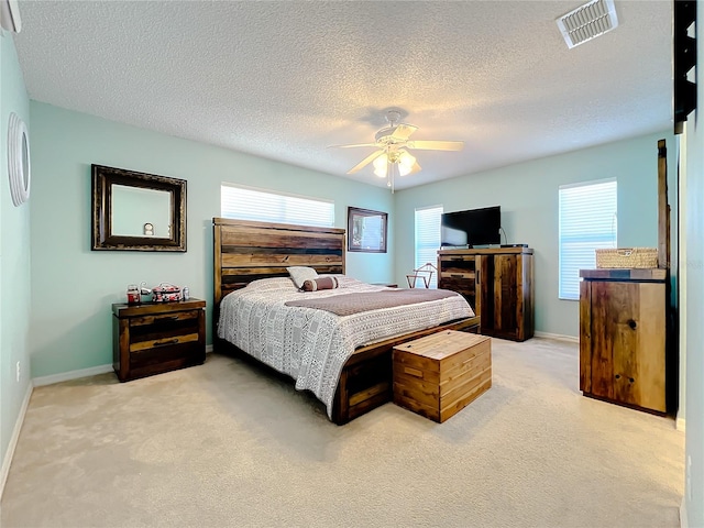 carpeted bedroom with a textured ceiling, ceiling fan, and multiple windows