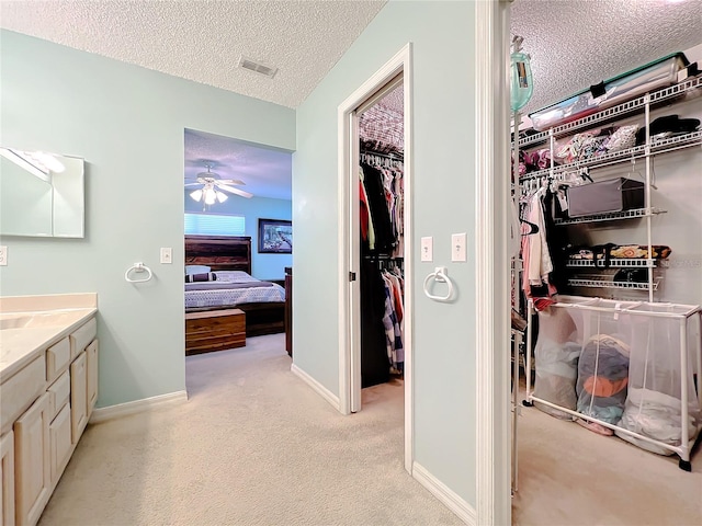 bathroom with a textured ceiling, vanity, and ceiling fan