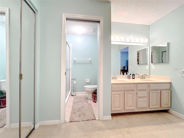 bathroom featuring a textured ceiling, double vanity, and toilet