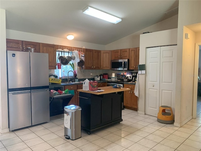 kitchen featuring vaulted ceiling, stainless steel appliances, light tile floors, and sink