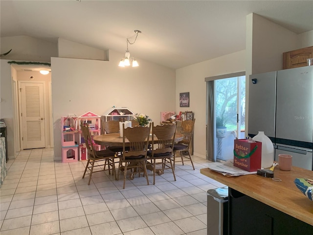 dining area featuring a notable chandelier, vaulted ceiling, and light tile flooring