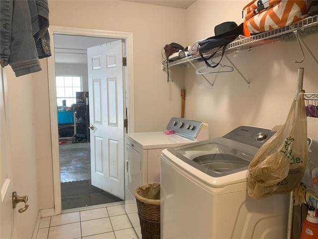 clothes washing area featuring light tile floors and washer and clothes dryer