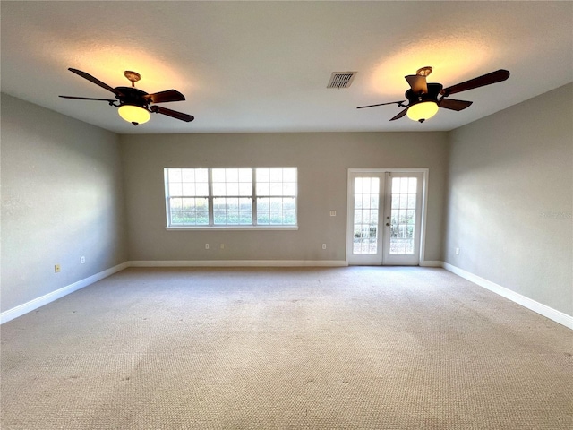 carpeted spare room featuring french doors and ceiling fan