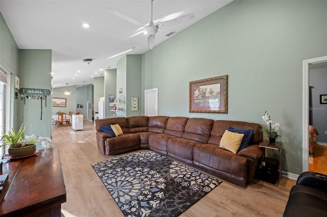 living room featuring high vaulted ceiling, light hardwood / wood-style floors, and ceiling fan