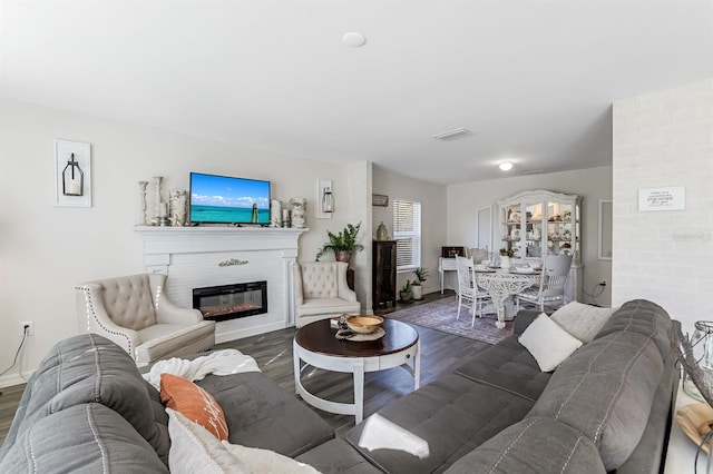 living room featuring a glass covered fireplace, wood finished floors, and visible vents