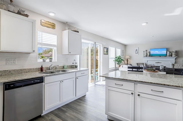 kitchen with white cabinets, dishwasher, light stone counters, light hardwood / wood-style floors, and sink