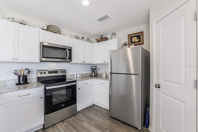 kitchen with hardwood / wood-style floors, appliances with stainless steel finishes, light stone countertops, and white cabinets