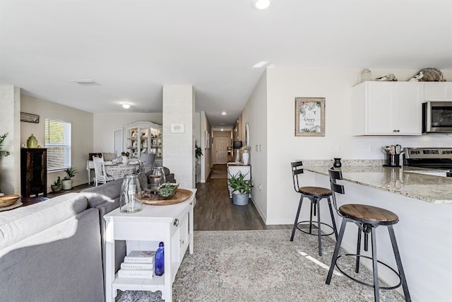 living room featuring light wood finished floors, recessed lighting, visible vents, and baseboards