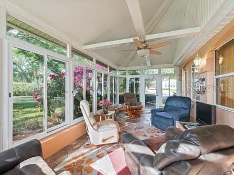 sunroom / solarium featuring ceiling fan and vaulted ceiling with beams