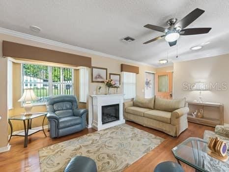 living room with ceiling fan, ornamental molding, and light hardwood / wood-style floors