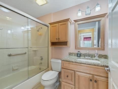 full bathroom featuring enclosed tub / shower combo, toilet, and large vanity