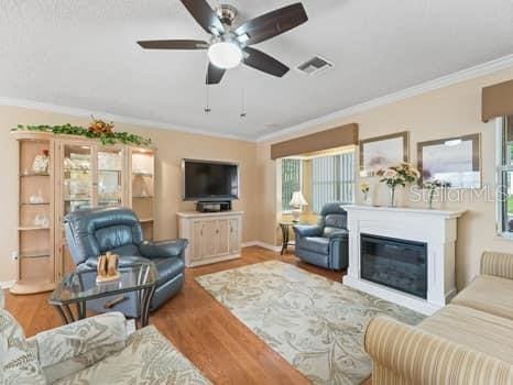 living room with light hardwood / wood-style flooring, crown molding, and ceiling fan