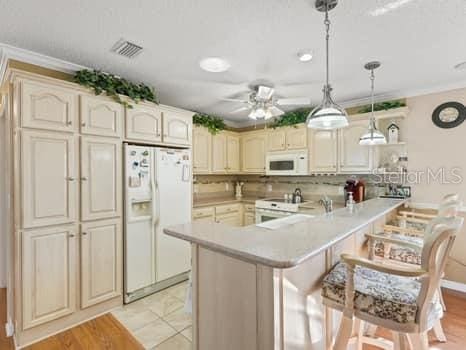 kitchen with decorative light fixtures, backsplash, a breakfast bar, ceiling fan, and white appliances