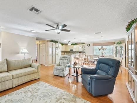 living room featuring a textured ceiling, ceiling fan, and light wood-type flooring