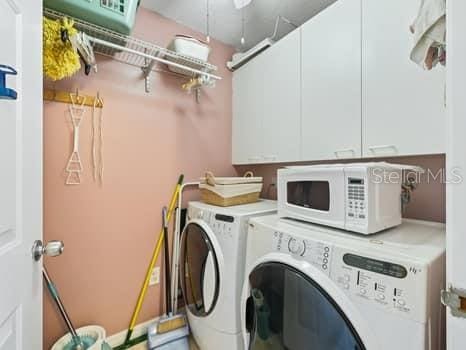 clothes washing area with cabinets and washer and clothes dryer