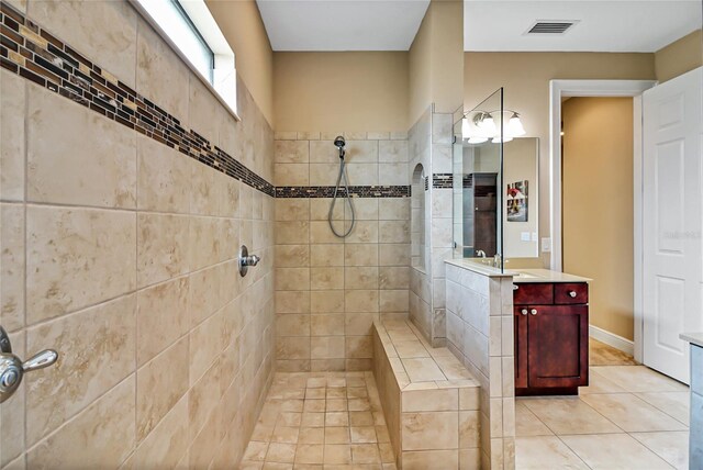 bathroom with a tile shower, tile floors, and large vanity