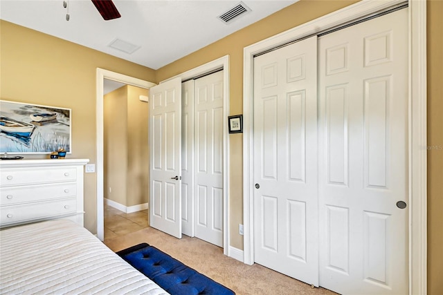 carpeted bedroom featuring multiple closets and ceiling fan