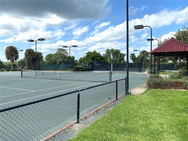 view of tennis court with a yard